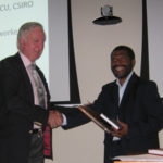 Dr Banabas receives the award from Dr Denis Blight